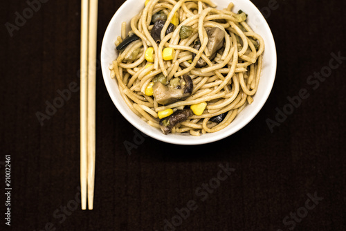 Plate of asian noddles in a white round bowl with chopsticks