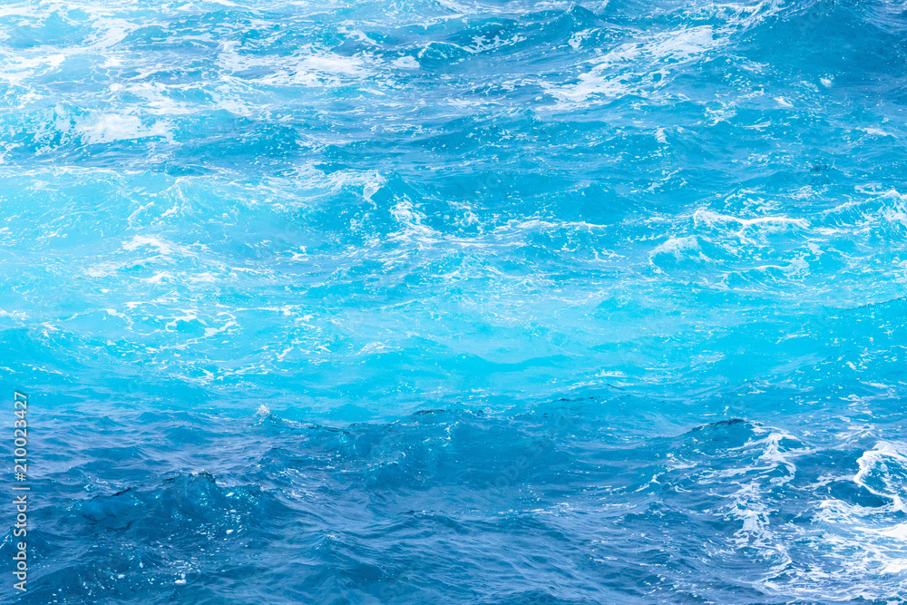 Atlantic ocean with blue water on a sunny day. Waves, foam and wake caused by cruise ship in the sea