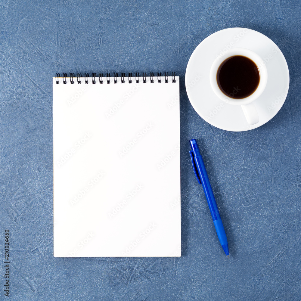 open notepad with clean white page, pen and coffee cup on aged dark blue stone table, top view open notepad with clean white page, pen and coffee cup on aged dark blue stone table, top view