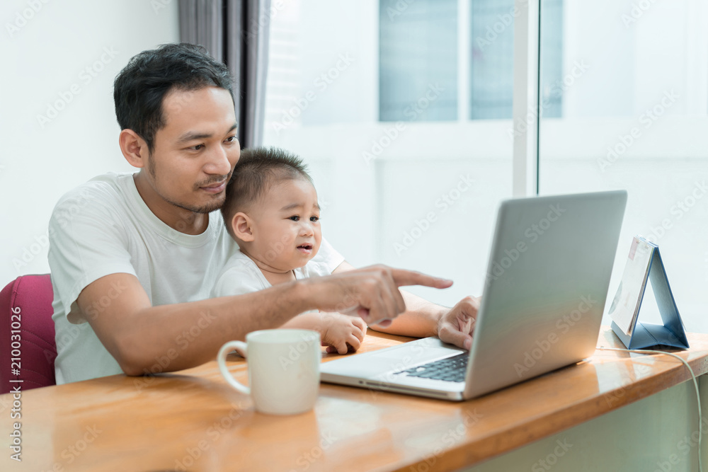 Asian father and little son typing someting on laptop computer on workplace at office home happiness laughing together, happy family concept. Asian father and little son typing someting on laptop computer on workplace at office home happiness laughing together, happy family concept.