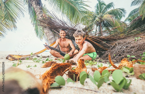 Playing in Robinzones: father and son built a hut from palm tree branches photo