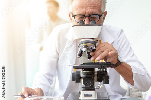 Doctor older or seriously scientist working with a microscope in Laboratory.