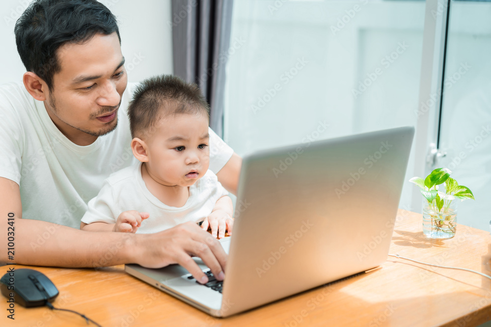 Asian father and little son typing someting on laptop computer on workplace at office home happiness laughing together, happy family concept. Asian father and little son typing someting on laptop computer on workplace at office home happiness laughing together, happy family concept.
