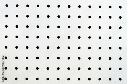 Symetrical holes on a white pegboard photo