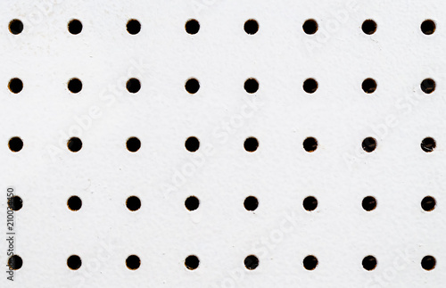 Close-up of symetrical holes on a white pegboard photo