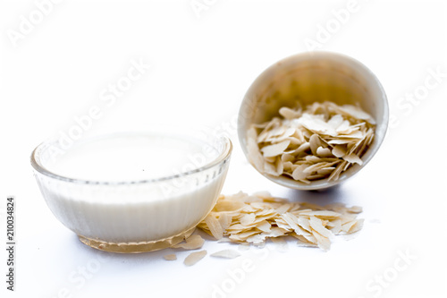 Ingredients of Poha kheer i.e. milk with flattened rice and sugar in a bowl isolated on white. photo