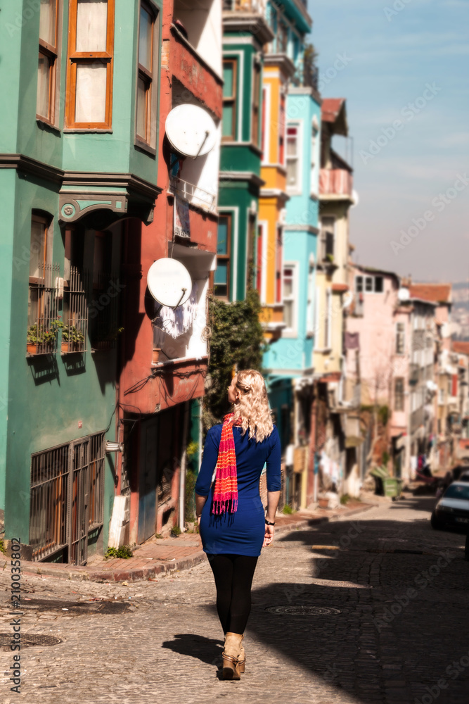 Beautiful girl in front of traditional colorful houses at Balat area. Istanbul