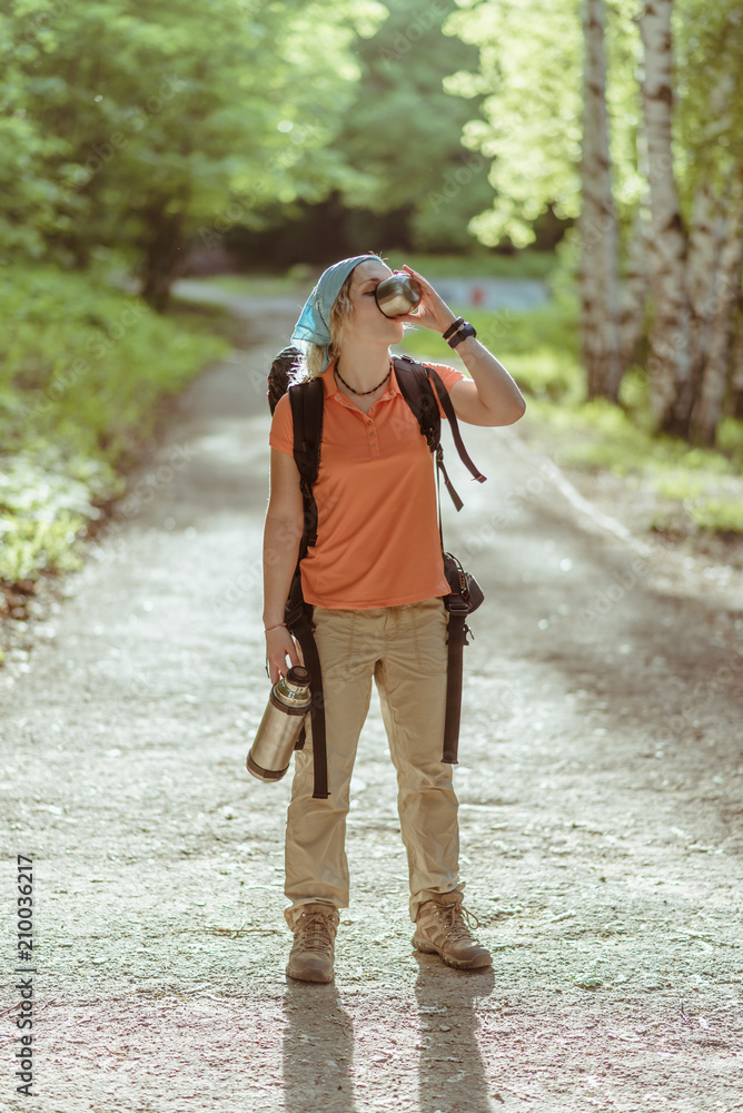 the tourist girl drinks tea from the term in the forest at sunset the tourist girl drinks tea from the term in the forest at sunset