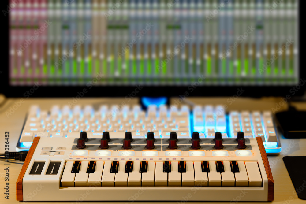 midi keyboard, audio signal level on screen. music production, home studio concept