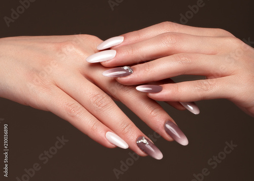 Beautiful classic manicure with crystals on female hand. Close-up. Picture taken in the studio