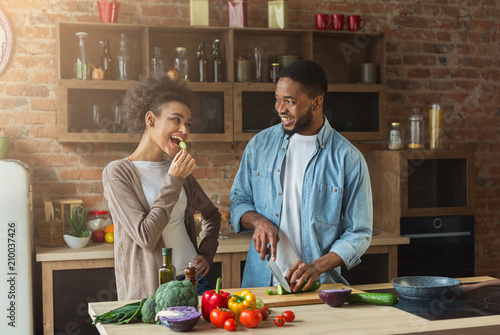 Happy african-american couple cooking in loft kitchen