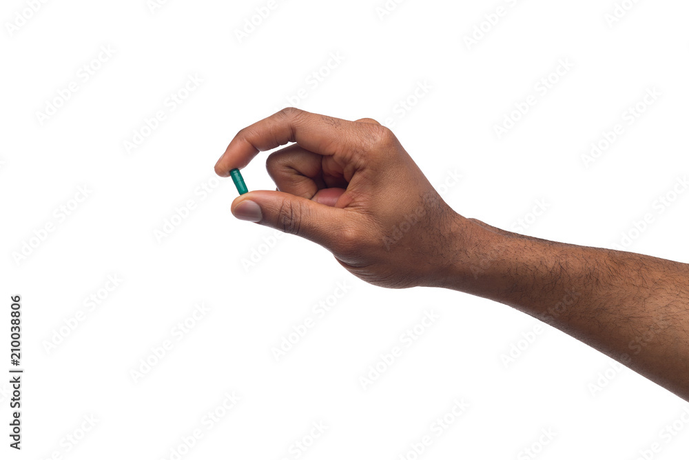 Black hand holding a pill isolated on white background Black hand holding a pill isolated on white background