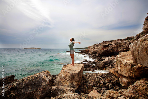 Fotobehang Woman with outstretched arms enjoying the wind and breathing fresh air on the ro