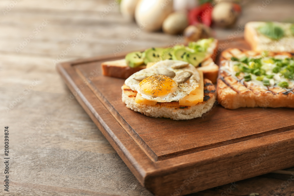 Different delicious toasts on wooden board, closeup Different delicious toasts on wooden board, closeup