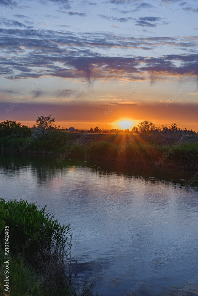 Silence, sunset in the steppe, beautiful clouds and the water surface of the canal.