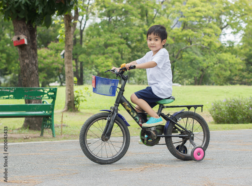 Fototapeta premium Asian cute boy ride a bicycle at park green nature background