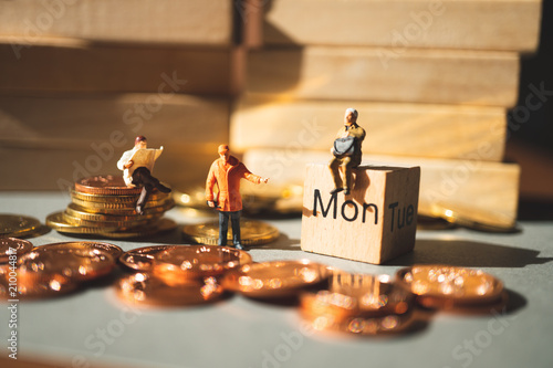 Miniature people, group of men take action on monday wooden block and stack coins using as business and industrial concept