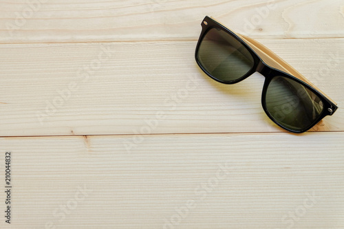 Top view and close up: Wooden sunglasses on brown wood background.