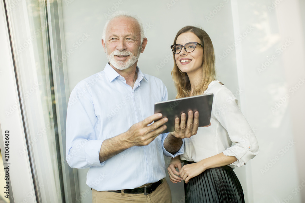Senior man presenting data to young woman on digital tablet Senior man presenting data to young woman on digital tablet