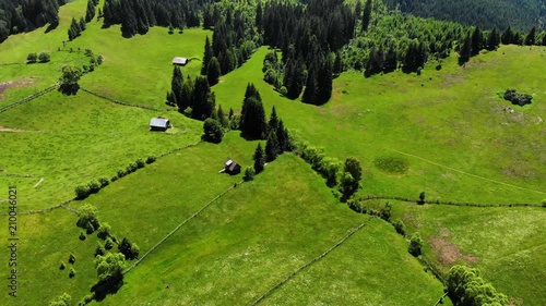 Panoramic view of idyllic mountain scenery with fresh green meadows in bloom on a beautiful sunny day in springtime. Aerial 4K view. Low air flight over mountain rural farm and meadow at sunny day photo