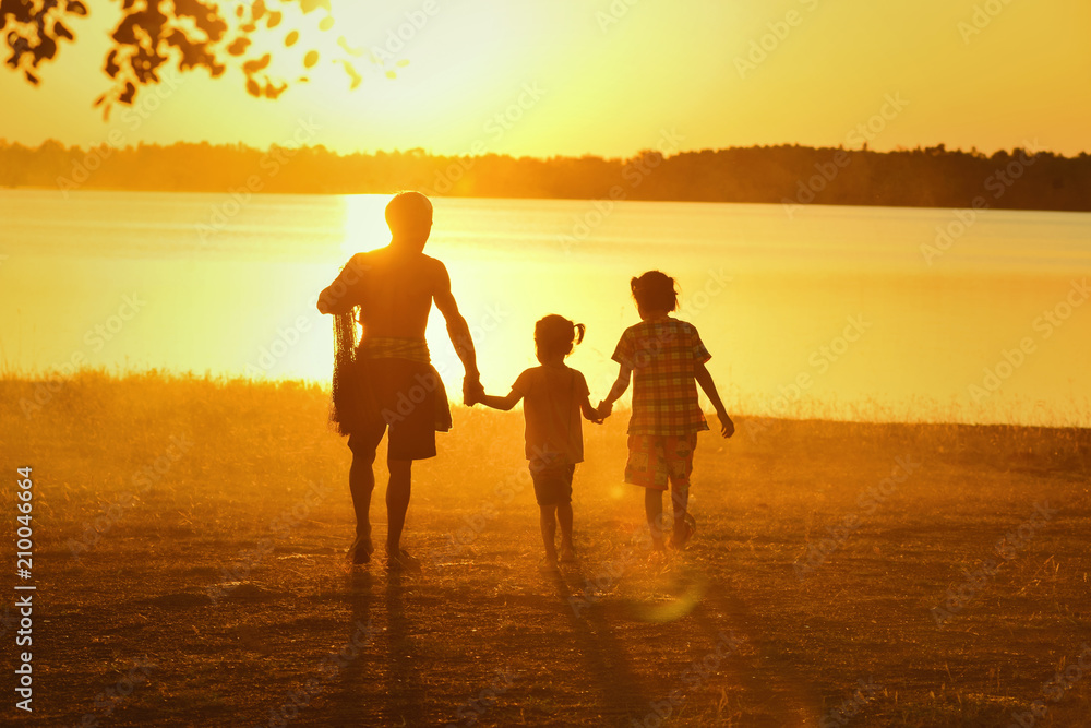 Fototapeta premium Happy loving family. Dad and his daughter playing outdoors. Father took the baby learn to walk at sunset.
