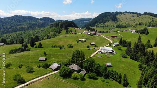 Panoramic view of idyllic mountain scenery with fresh green meadows in bloom on a beautiful sunny day in springtime. Aerial 4K view. Low air flight over mountain rural farm and meadow at sunny day photo
