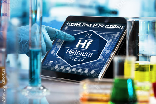 Scientist working on the digital tablet data of the chemical element Hafnium Hf / researcher consulting information on the computer of the periodic table of elements 