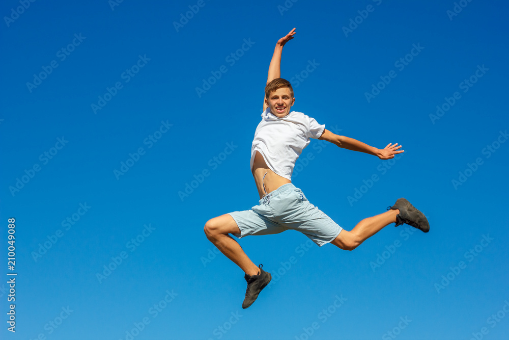 happy boy jumping in the blue sky , concept of happiness