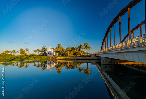 View of a church with a reflection in the water and a bridge across the river in the Alboraya region. Valencia, Spain photo