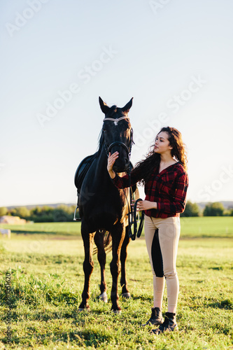 Young woman dressed casually petting black horse