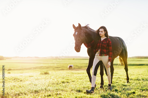 Young woman standing next to her black horse