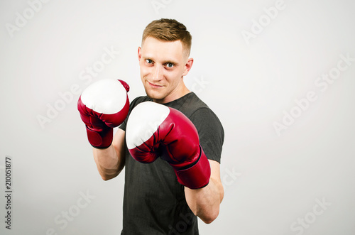 Young man in red boxing gloves on a light background.