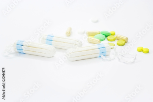 Tampons and pills on a white background