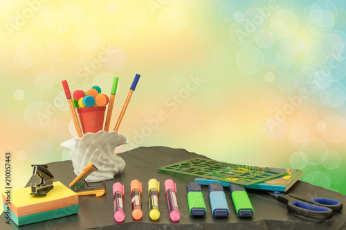 Back to school. Colorful school equipment on slate plate in front of pastel colored bright bokeh background. Space for your text or dsiplay product montage. photo