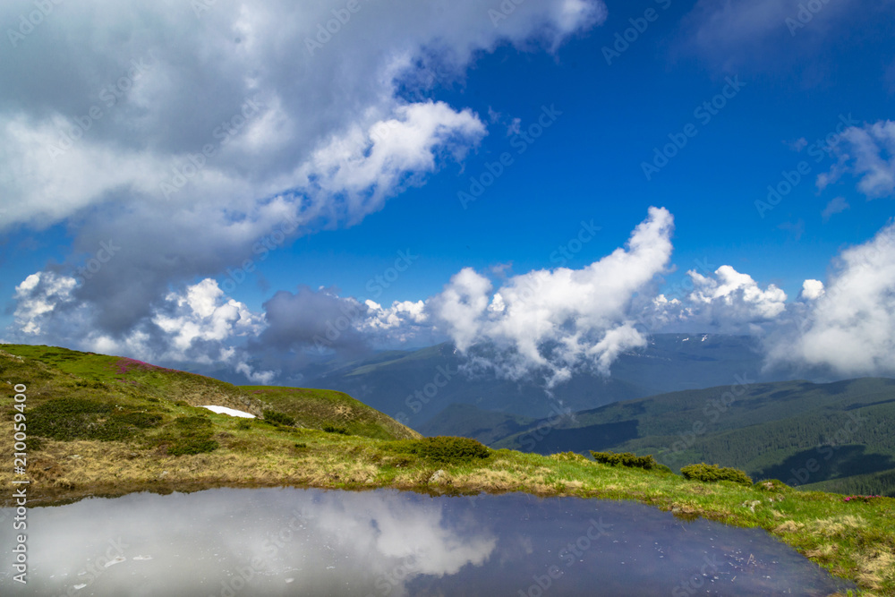 Clear Alpine lake with reflection of blue cloudy sky