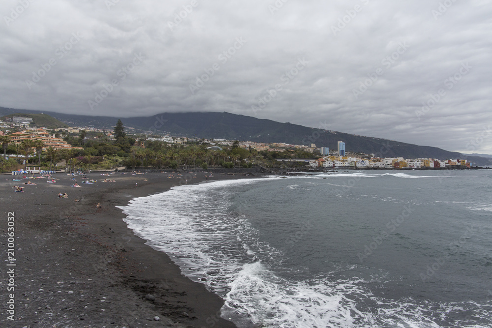 Puerto de la Cruz, Tenerife, Canary Islands - view of colorful houses, sea and volcanic-sand beach. Black beach in tenerife Puerto de la Cruz, Tenerife, Canary Islands - view of colorful houses, sea and volcanic-sand beach. Black beach in tenerife