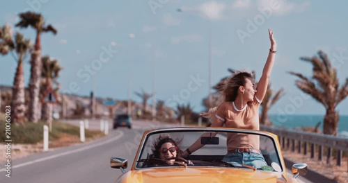 Women having fun and enjoying the sun in convertible car