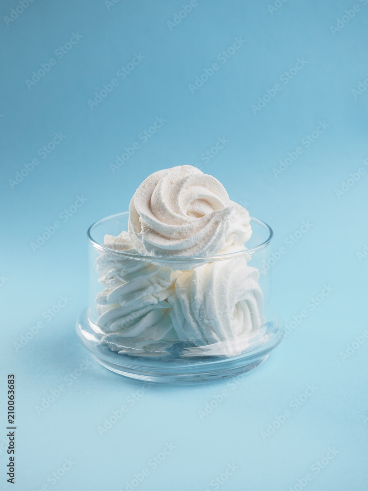 White homemade zephyr on glass crocheted jacket. blue isolated background White homemade zephyr on glass crocheted jacket. blue isolated background