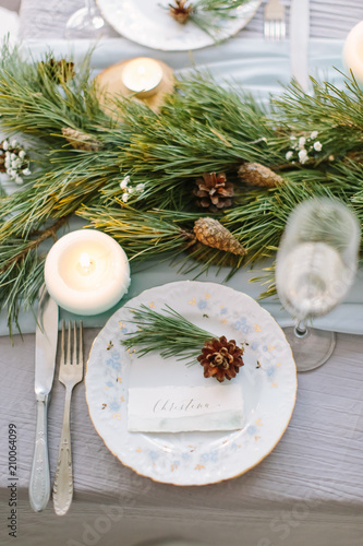 Aerial view of winter green pine garland on a wedding table with white plates and and blue candles