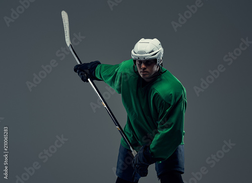 Photography Professional hockey player trains in full equipment with gaming stick against a gray background