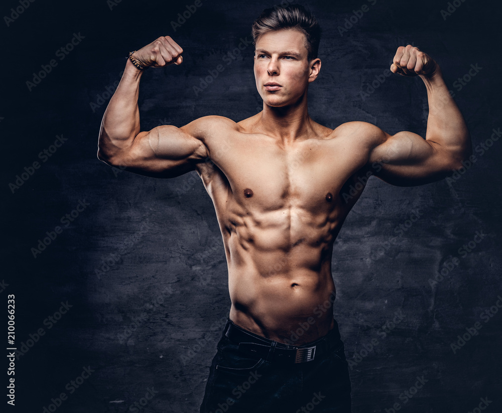 Beautiful shirtless young man model with nice muscular body posing at a studio.