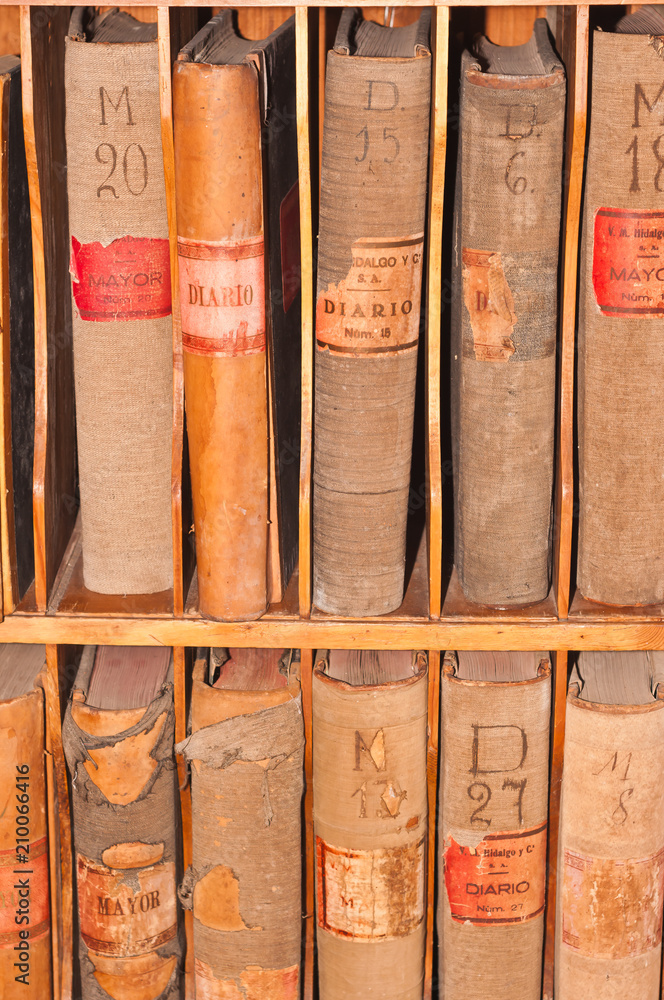 Front view, close up of bound records, hundreds of years old in a book cabinet of a fourth generation winery in the southeast region of wine country of Spain Front view, close up of bound records, hundreds of years old in a book cabinet of a fourth generation winery in the southeast region of wine country of Spain