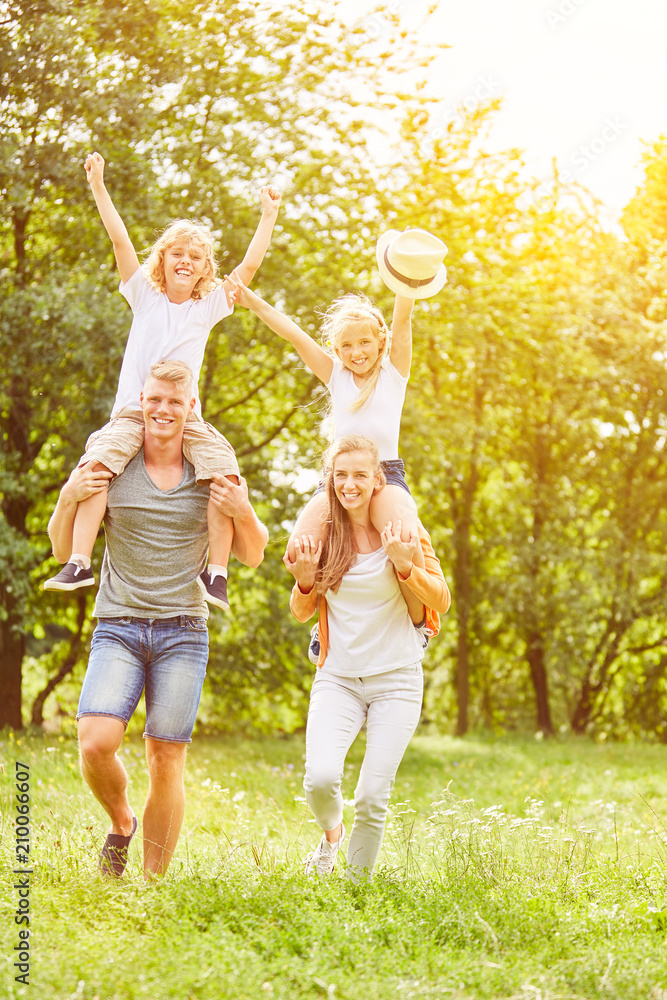 Fototapeta premium Eltern tragen Kinder huckepack im Sommer