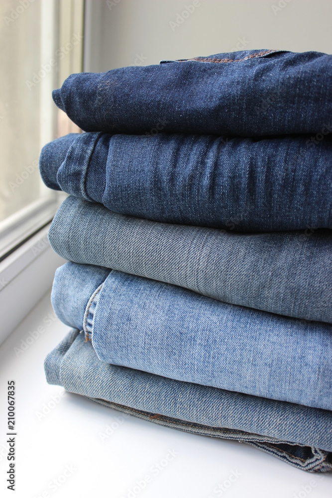 A lot of things blue jeans stacked in a pile on white background A lot of things blue jeans stacked in a pile on white background
