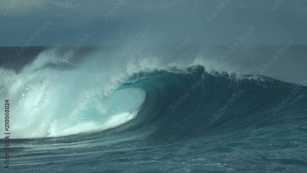 SLOW MOTION, CLOSE UP: Big tube wave leaving a cool mist of glassy water droplets in the air while it closes in on a remote exotic beach. Perfect shot of massive emerald swell near tropical island. SLOW MOTION, CLOSE UP: Big tube wave leaving a cool mist of glassy water droplets in the air while it closes in on a remote exotic beach. Perfect shot of massive emerald swell near tropical island.