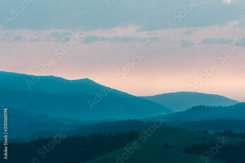 Beautiful dramatic sunrise in the mountains. Landscape with sunlight shining through orange clouds © Pavel