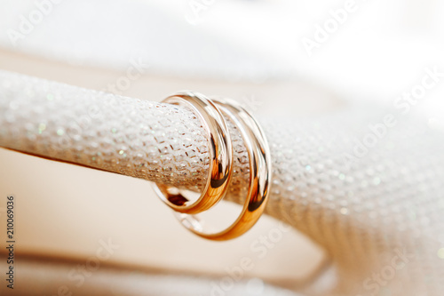 Golden wedding rings on bride shoes with rhinestones. Wedding jewelry details. Symbol of love and marriage.