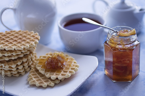 Breakfast. Fika. White cup of tea with thin waffles and lemon jam.