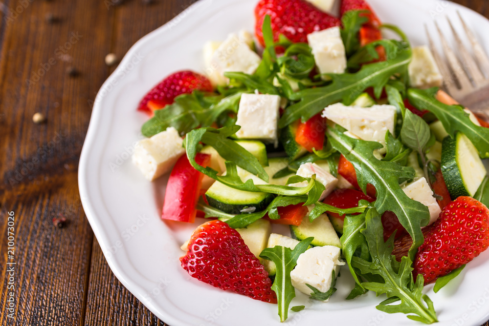 Fresh vegetable strawberry salad on white plate on natural rustic desk. Fresh vegetable strawberry salad on white plate on natural rustic desk.