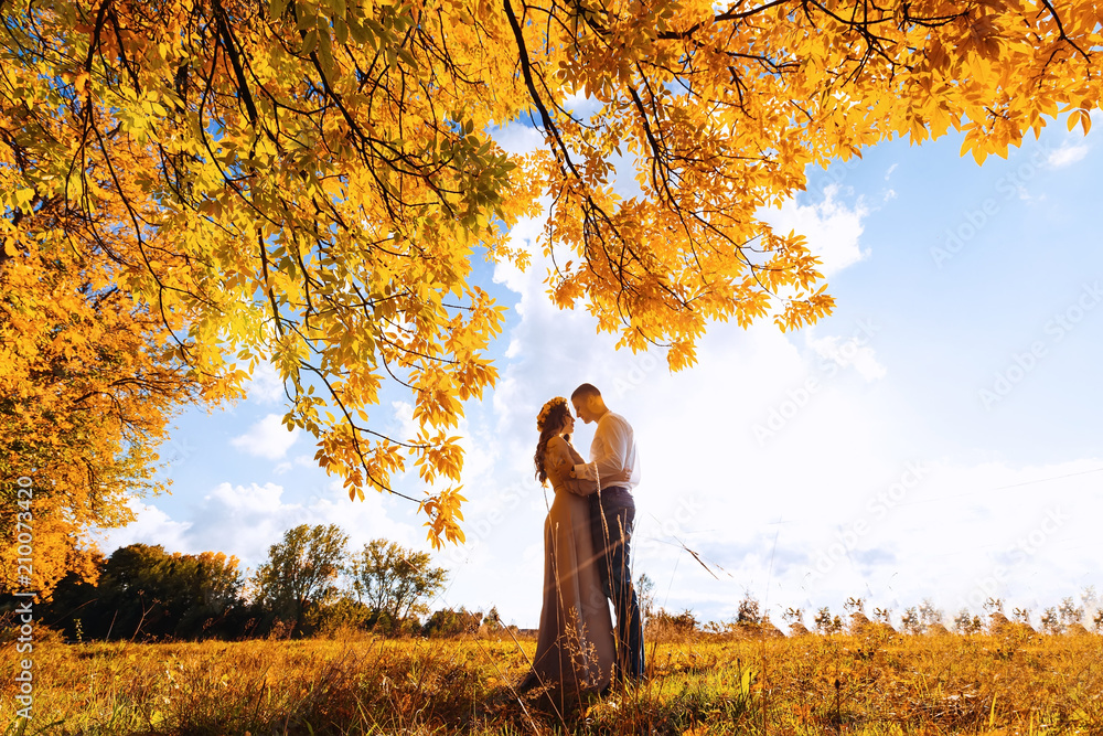 lovers standing face to face under the branches of trees on a beautiful autumn day